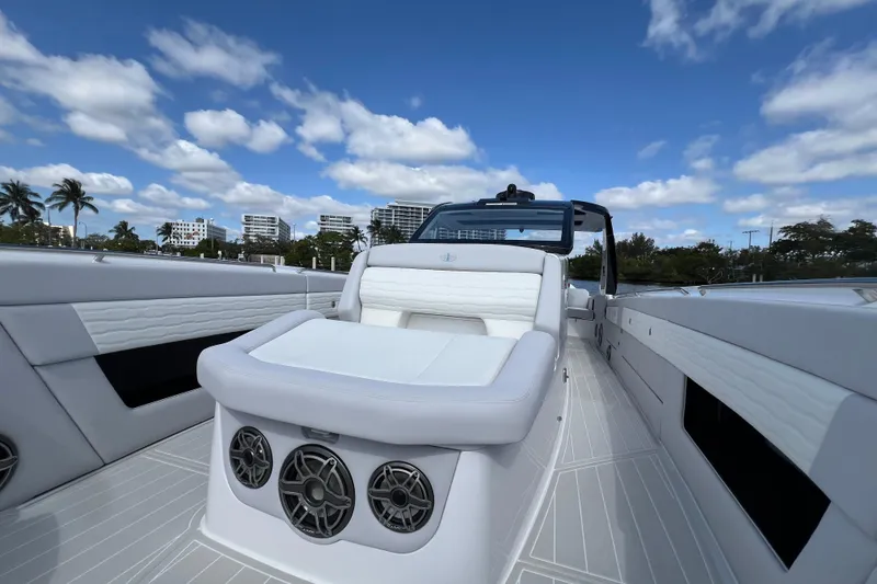 Slide: The Image of 2025 Cigarette 41 Nighthawk luxury boat interior with white seating and speakers under blue sky. - 33