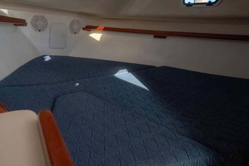 Slide: The Image of Interior cabin of 2021 NorthCoast 315 HT boat with blue quilted bedding. - 10