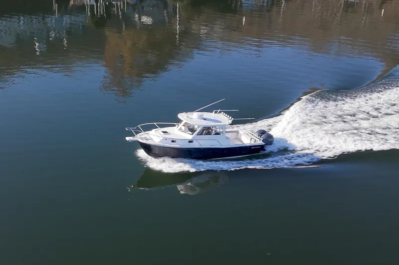 Slide: The Image of 2021 NorthCoast 315 HT boat cruising on calm water, creating a wake. - 25