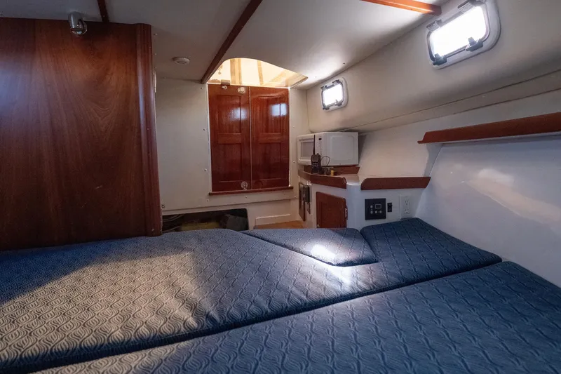 Slide: The Image of 2021 NorthCoast 315 HT cabin interior with blue bedding and wooden accents. - 9