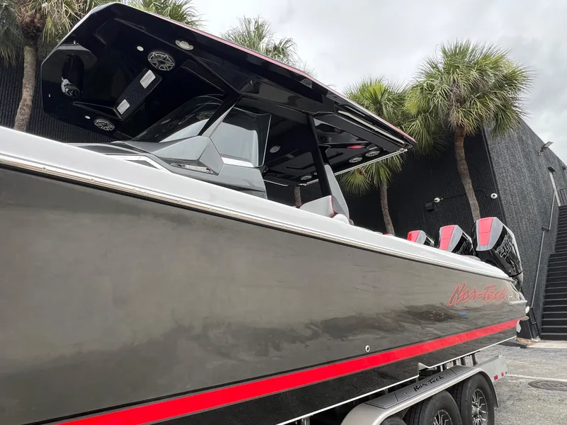 Slide: The Image of 2025 Nor-Tech 400 Supersport boat with sleek design and red accents, parked near palm trees. - 9