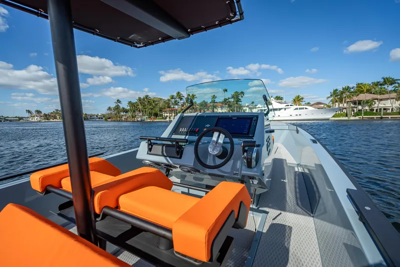 Slide: The Image of 2024 Goldfish 28 Tender boat with orange seats and modern dashboard on the water. - 16