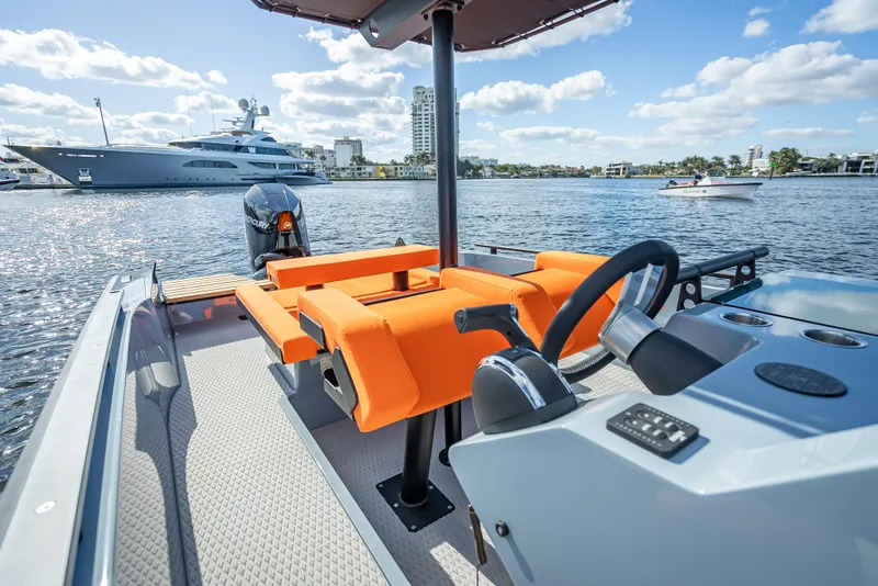 Slide: The Image of 2024 Goldfish 28 Tender boat with orange seating and modern controls on a sunny day. - 8