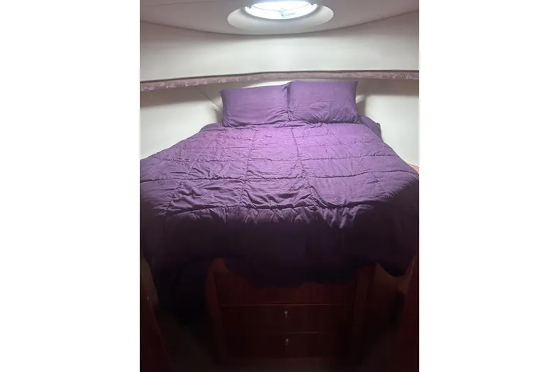 Slide: The Image of 2008 Silverton 36 Convertible cabin with purple bedding and overhead skylight. - 11
