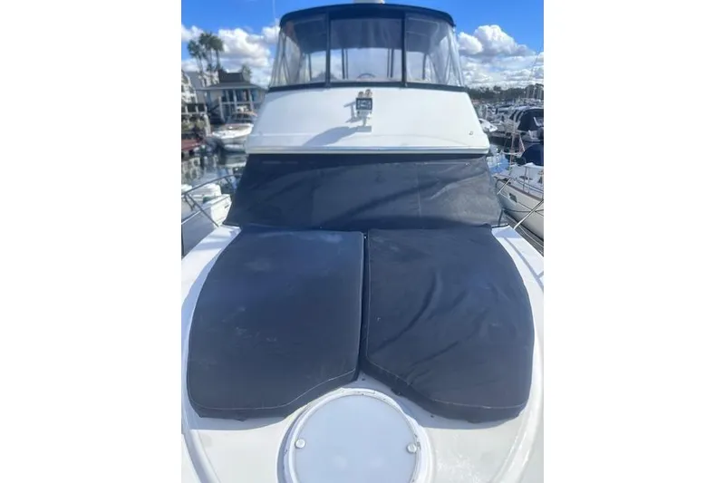 Slide: The Image of 2008 Silverton 36 Convertible yacht with black covers, docked in a marina. - 2