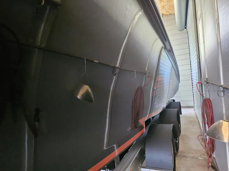 Slide: The Image of 2021 Statement 350 Open boat in storage, side view with trailer wheels visible. - 31