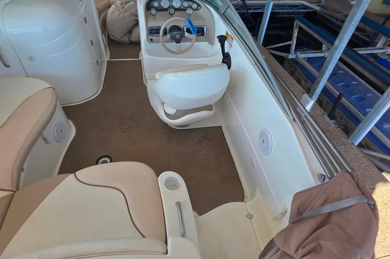 Slide: The Image of 2005 Glastron DX 235 boat interior with beige seating and steering console. - 11