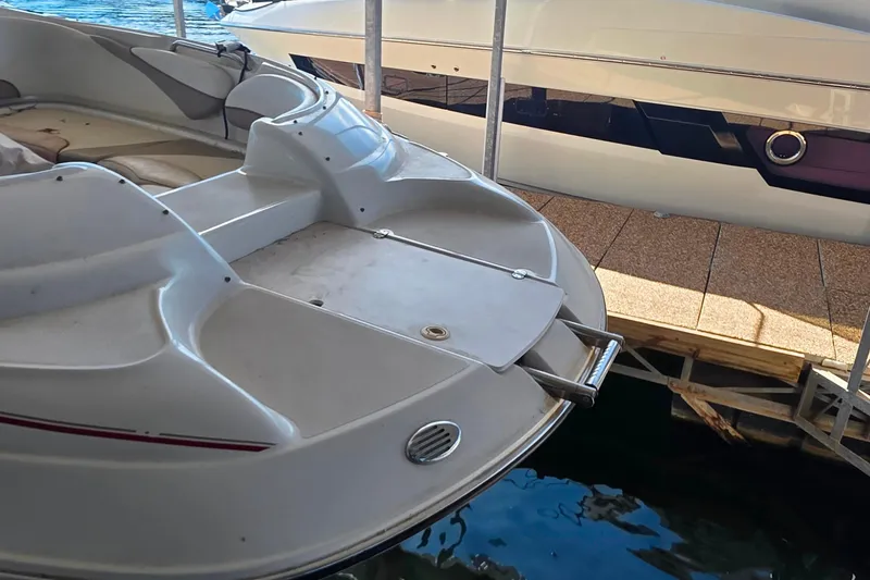 Slide: The Image of 2005 Glastron DX 235 boat docked, showcasing rear seating and swim platform. - 6