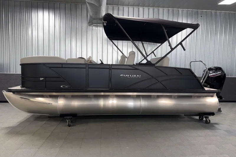 Slide: The Image of 2026 Sylvan Mirage 8520 CLZ DH PTS Tritoon in showroom, featuring sleek design and Mercury engine. - 21