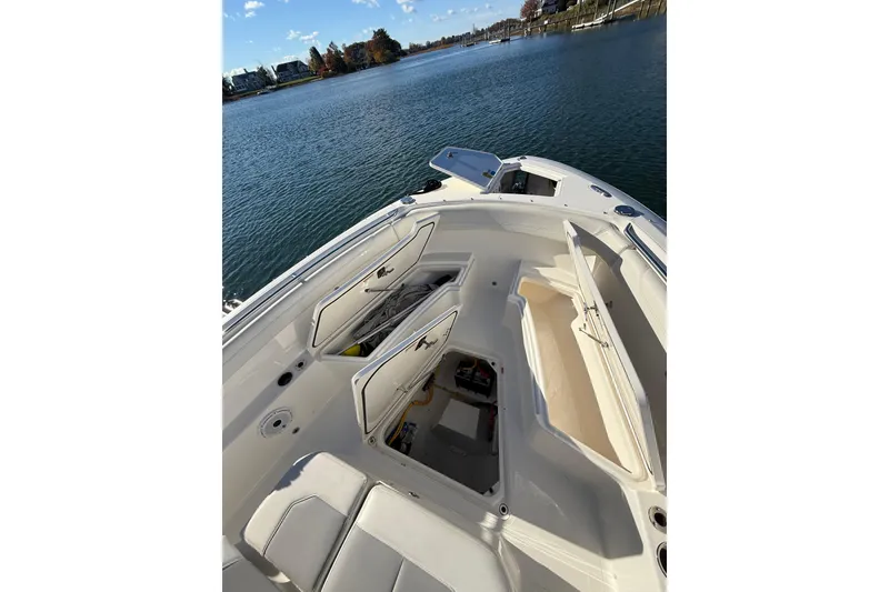 Slide: The Image of 2020 Pursuit S 288 Sport boat with open storage compartments on a calm lake. - 21
