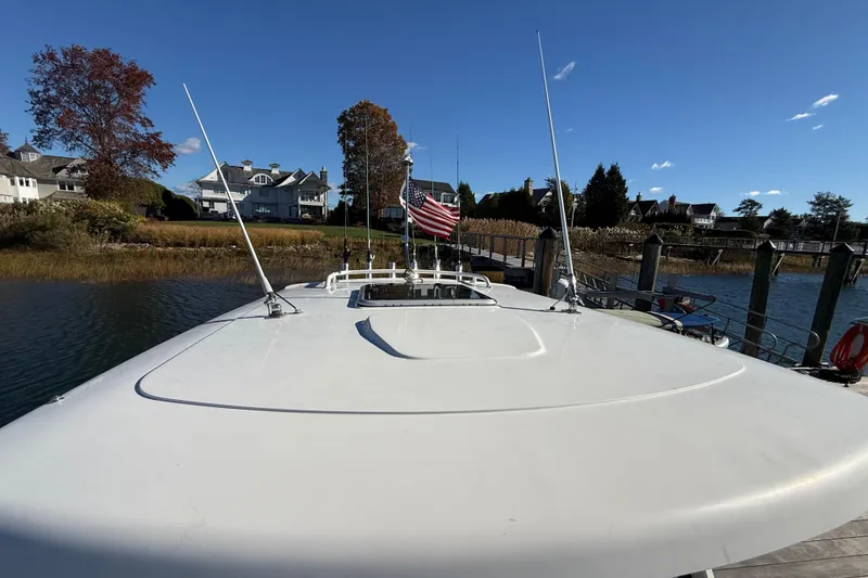 Slide: The Image of 2020 Pursuit S 288 Sport boat docked, American flag, waterfront homes, clear blue sky. - 6