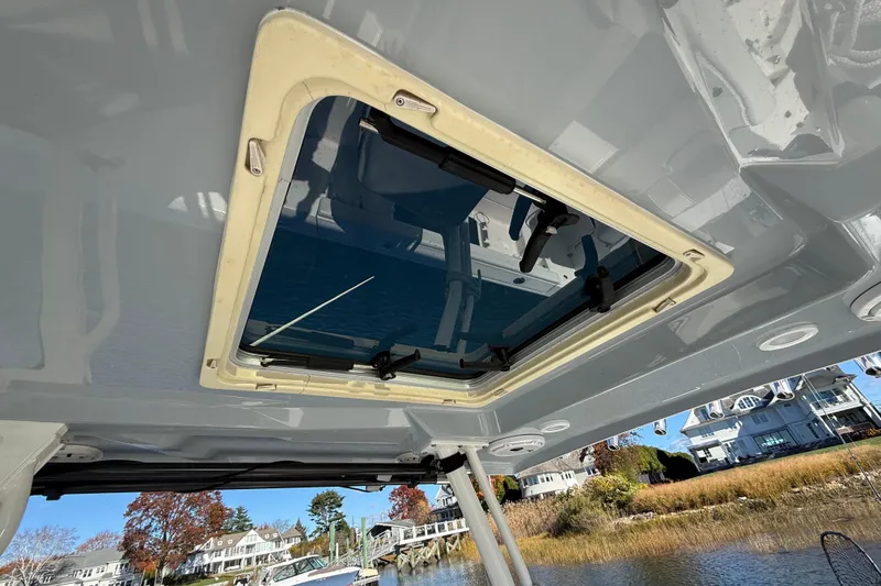 Slide: The Image of 2020 Pursuit S 288 Sport boat with open sunroof, docked near waterfront homes. - 7