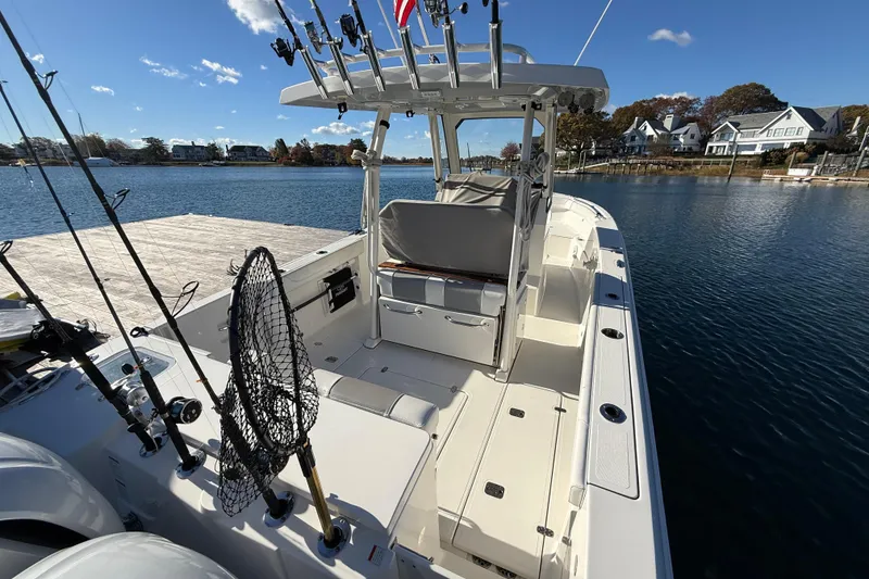 Slide: The Image of 2020 Pursuit S 288 Sport boat docked, equipped with fishing rods and net, under clear skies. - 9