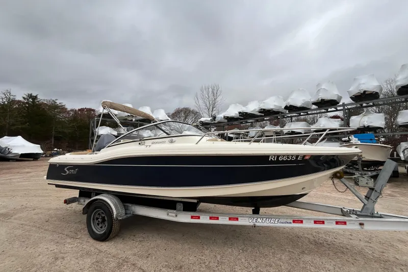 The Image of 2015 Scout 210 Dorado boat on trailer, parked outdoors under cloudy sky. - 0