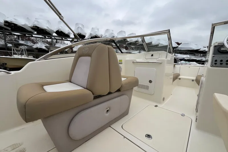 Slide: The Image of 2015 Scout 210 Dorado boat interior with beige seating and console, under cloudy sky. - 10