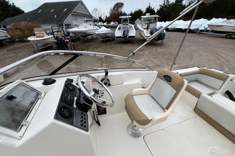 Slide: The Image of 2015 Scout 210 Dorado boat interior with steering wheel and seating, parked in a marina. - 14