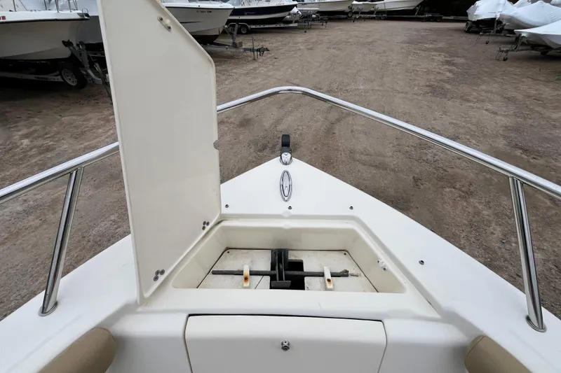 Slide: The Image of 2015 Scout 210 Dorado boat bow with open storage compartment, parked on gravel. - 24