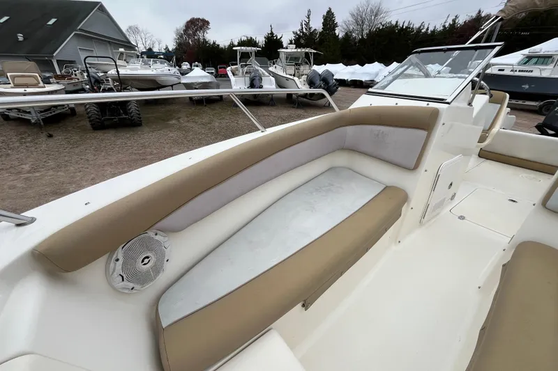 Slide: The Image of 2015 Scout 210 Dorado boat interior with beige seating and speaker, parked outdoors. - 25