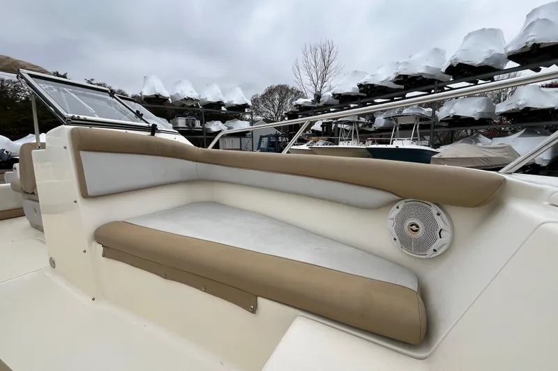 Slide: The Image of 2015 Scout 210 Dorado boat interior with cushioned seating and speaker, stored outdoors. - 26