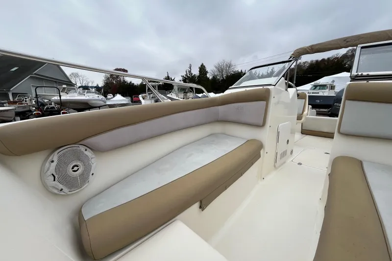 Slide: The Image of 2015 Scout 210 Dorado boat interior with beige seating and speaker, docked outdoors. - 27