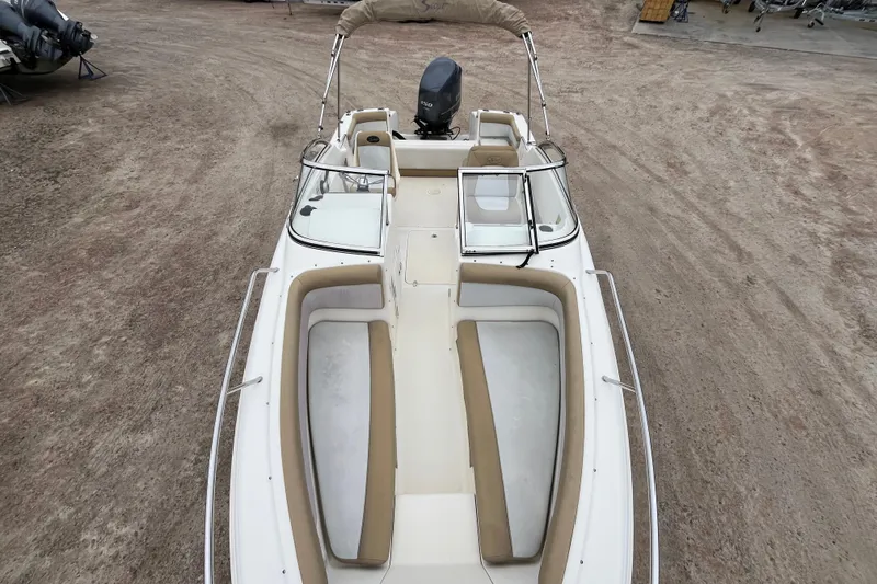 Slide: The Image of 2015 Scout 210 Dorado boat with beige seating and outboard motor, parked on dirt. - 29
