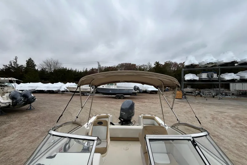 Slide: The Image of 2015 Scout 210 Dorado boat with canopy in a storage yard under cloudy skies. - 32