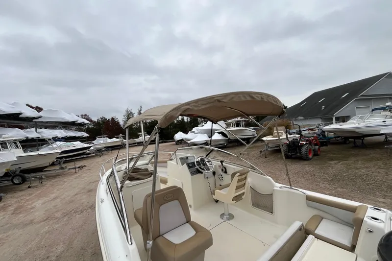 Slide: The Image of 2015 Scout 210 Dorado boat with canopy, parked in a marina with other boats. - 33