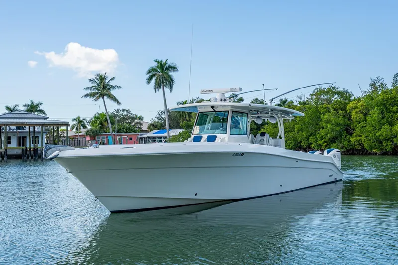 Slide: The Image of 2018 HCB 42 Siesta boat on calm water with lush greenery and blue sky. - 42