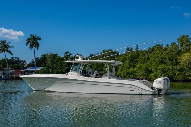 Slide: The Image of 2018 HCB 42 Siesta boat on calm water, surrounded by lush greenery and palm trees. - 48