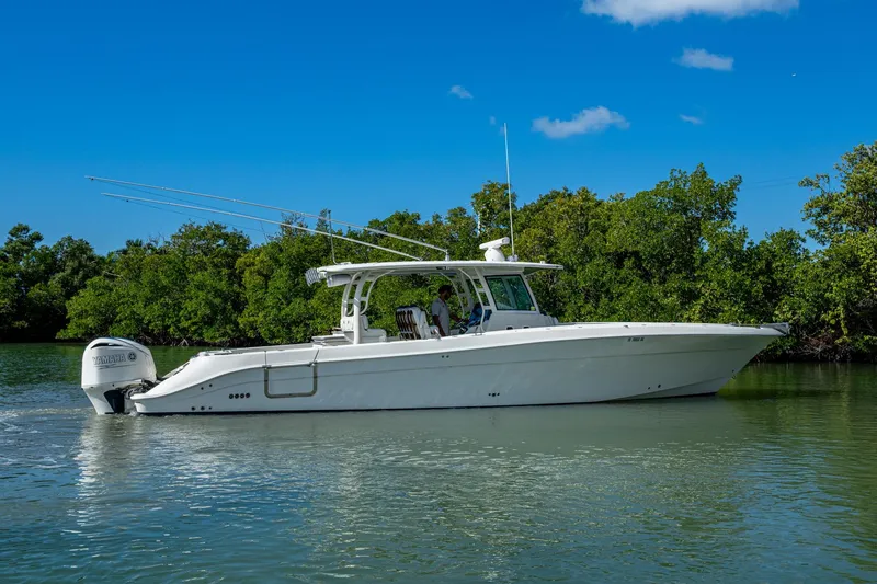 Slide: The Image of 2018 HCB 42 Siesta boat cruising on calm water, surrounded by lush greenery. - 56