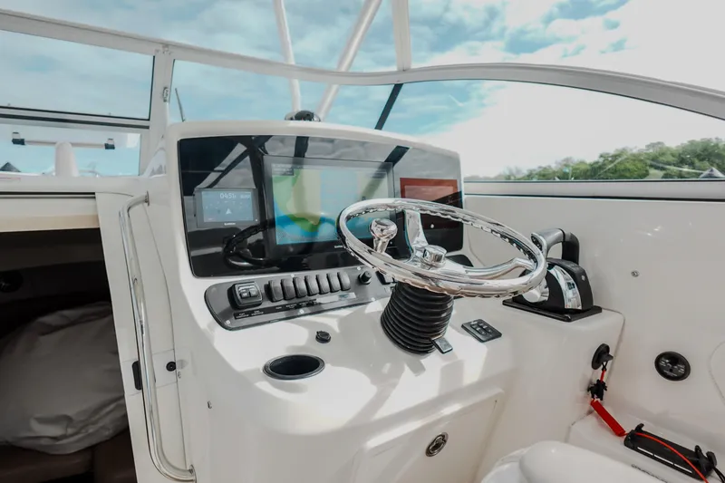 Slide: The Image of 2007 Boston Whaler 305 Conquest helm with steering wheel and navigation controls. - 27