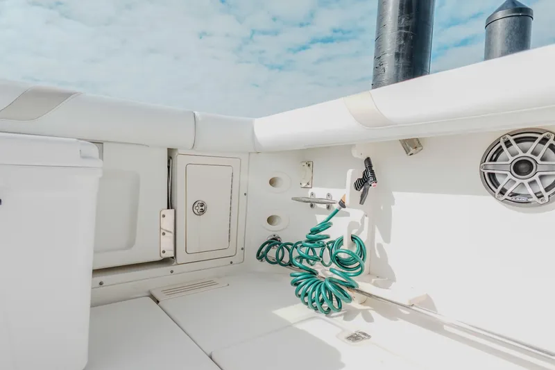Slide: The Image of 2007 Boston Whaler 305 Conquest boat interior with storage, speaker, and coiled hose. - 40