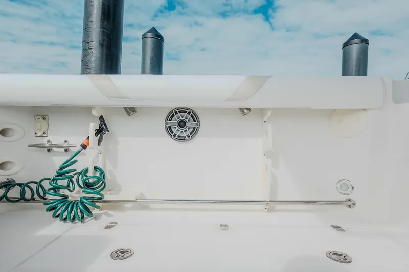 Slide: The Image of 2007 Boston Whaler 305 Conquest boat deck with hose and speaker, under blue sky. - 41