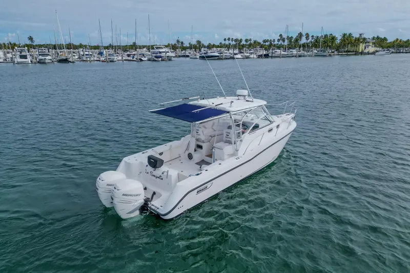 Slide: The Image of 2007 Boston Whaler 305 Conquest boat on water near marina, clear sky background. - 45