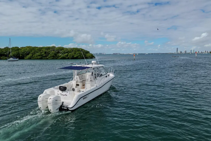 Slide: The Image of 2007 Boston Whaler 305 Conquest cruising on a scenic waterway under a partly cloudy sky. - 6
