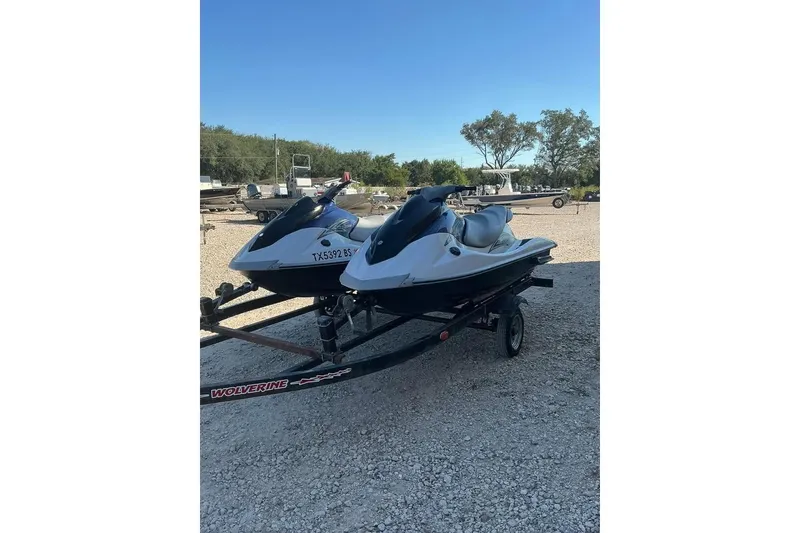 The Image of 2012 Yamaha WaveRunner VX Cruiser jet skis on a trailer in a gravel lot. - 1