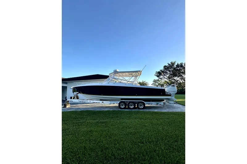 The Image of 2006 Contender 35 Express Side Console boat on trailer, parked outdoors. - 0
