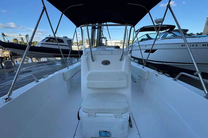 Slide: The Image of 2023 Edgewater 188CC boat interior with seating and canopy, docked alongside other boats. - 14