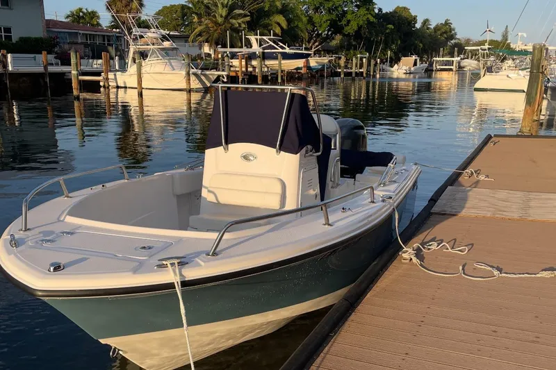 Slide: The Image of 2023 Edgewater 188CC boat docked in a marina, surrounded by calm water and other boats. - 6