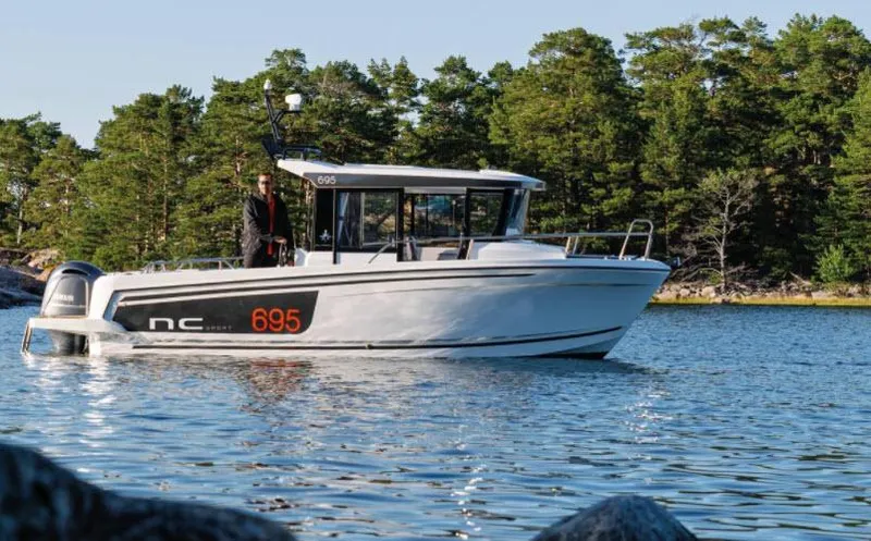 The Image of 2022 Jeanneau NC 695 Sport Serie 2 boat on a serene lake with forest backdrop. - 1
