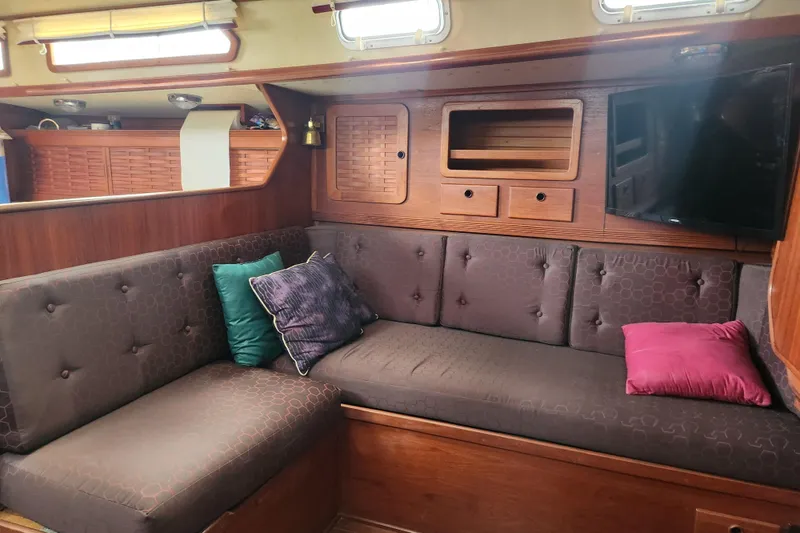 Slide: The Image of 1988 Sabre 42 yacht interior with cozy seating, cushions, and wooden cabinetry. - 24