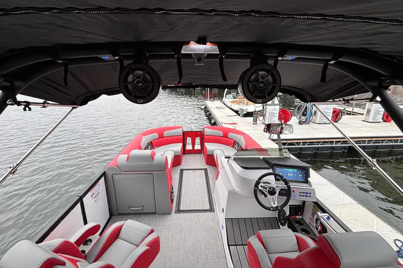 Slide: The Image of 2025 Montara 25 Surf Boss boat interior with red and gray seating, docked by the water. - 18