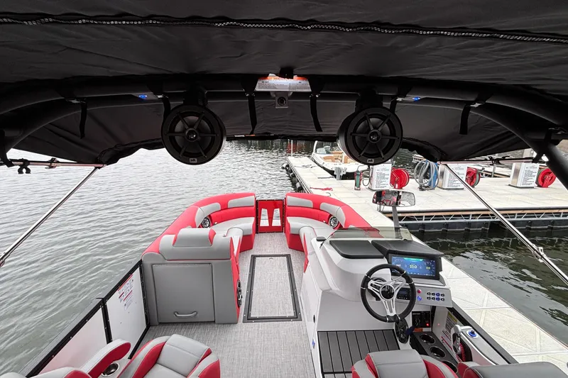 Slide: The Image of 2025 Montara 25 Surf Boss boat interior with red and gray seating, docked by the water. - 19