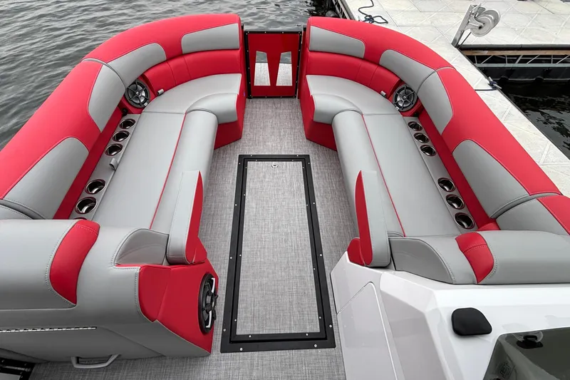 Slide: The Image of 2025 Montara 25 Surf Boss boat interior with red and gray seating, docked by the water. - 20