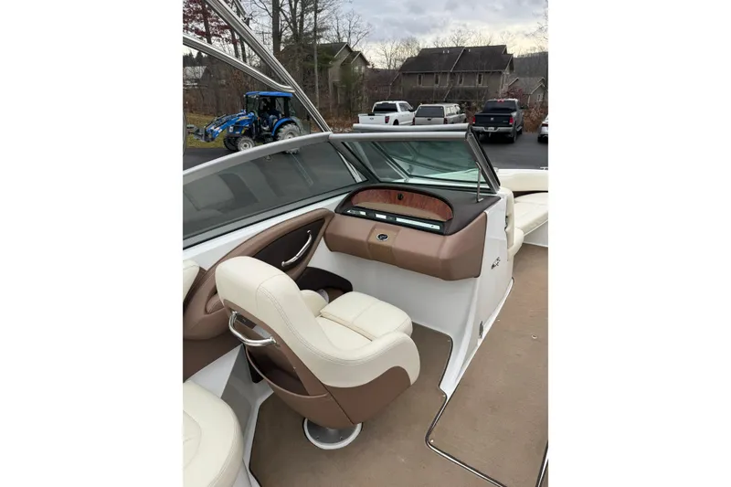 Slide: The Image of 2009 Cobalt 242 boat interior with beige and brown seating, parked outdoors. - 10