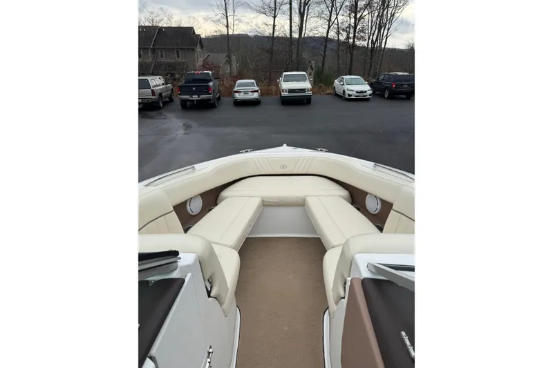 Slide: The Image of 2009 Cobalt 242 boat interior with beige seating, parked cars in the background. - 11