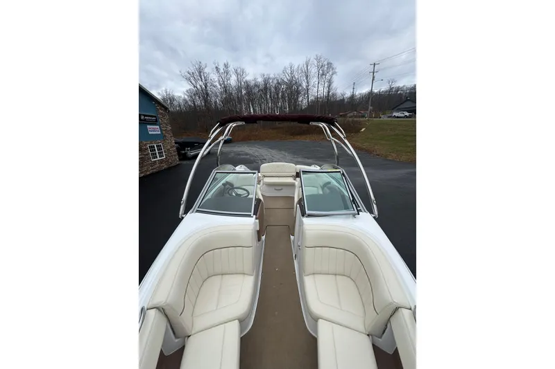 Slide: The Image of 2009 Cobalt 242 boat with white interior, parked outdoors on a cloudy day. - 12