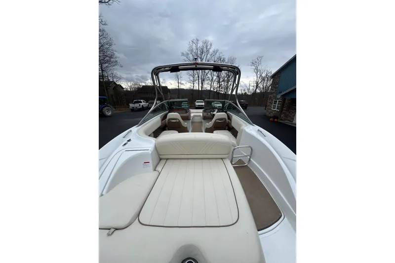 Slide: The Image of 2009 Cobalt 242 boat interior with white seating, parked outdoors under cloudy skies. - 7