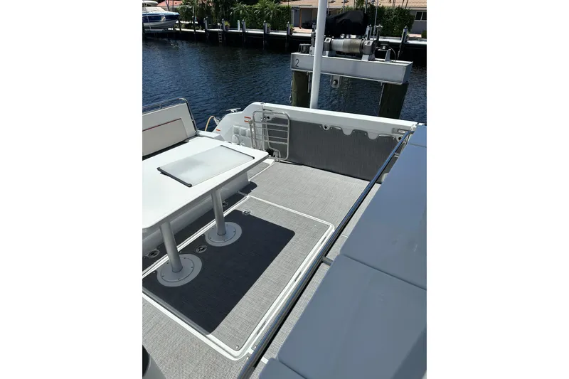 Slide: The Image of 2022 Jeanneau Leader 12.5 WA boat deck with table, docked by the water. - 17