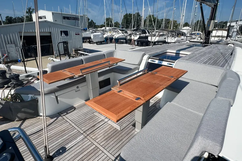 Slide: The Image of 2024 Beneteau First 53 yacht deck with wooden tables and cushioned seating. - 10